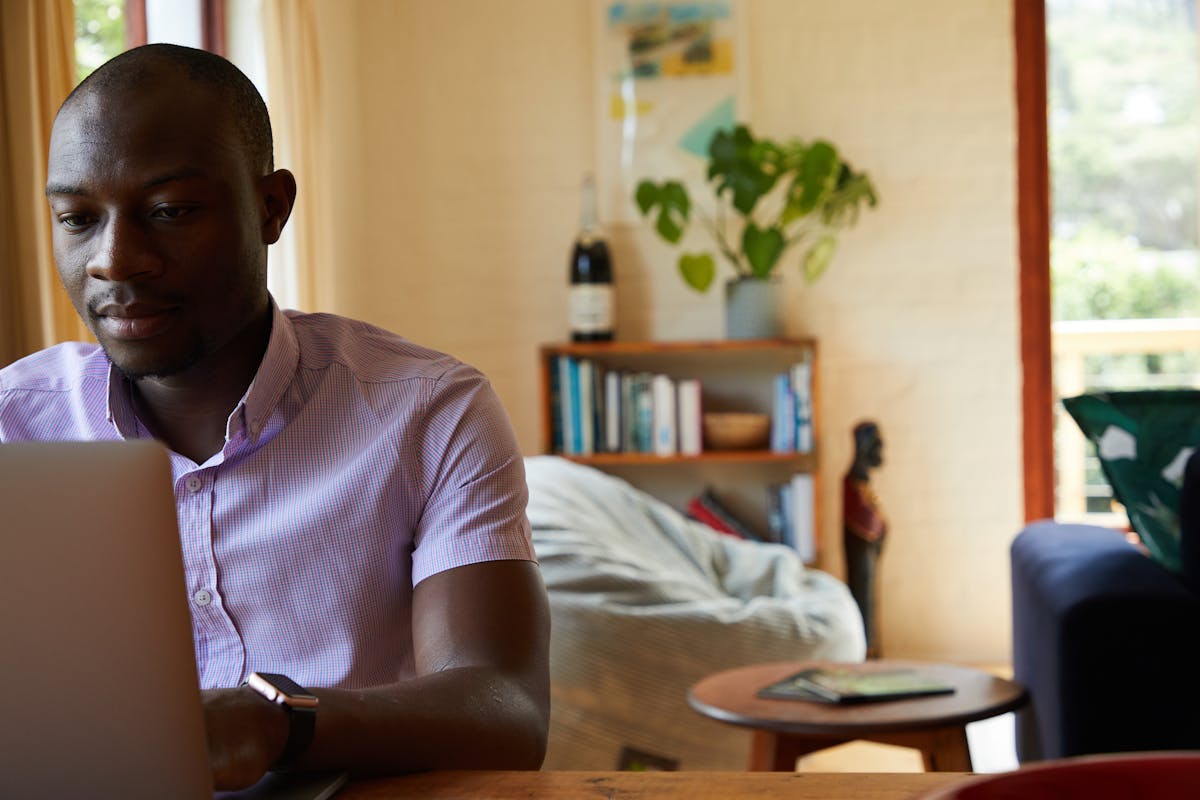 African male professional working on a laptop from a home office